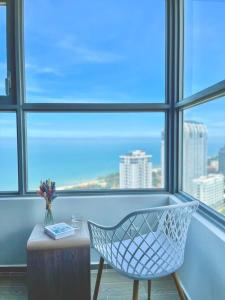 a white chair in front of a window with a table at Căn hộ The Song Du lịch biển Tháp Tam Thắng INFINITY POOL FREE IN SIDE THE SEA in Vung Tau