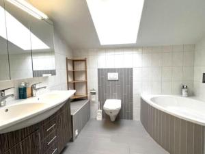 a bathroom with a sink and a tub and a toilet at Bell air Max in Les Hauts-Geneveys