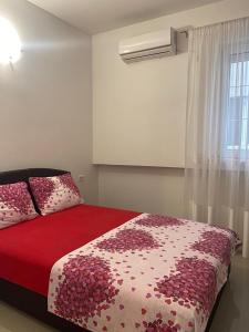 a bedroom with a red and white bed and a window at Marina Luka in Bar