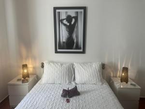 a bedroom with a white bed with a picture on the wall at Central Tavira apartment, Casa Oliverio in Tavira