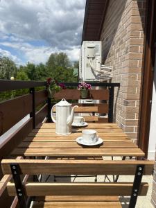 a wooden table on a balcony with cups and saucers at Apartament Spokojny in Łańcut