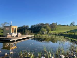 a dock with chairs and a house on a lake at "The Studio" Contemporary studio with organic swimming pool in Skelsmergh