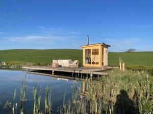 a tiny house on a dock next to a body of water at "The Studio" Contemporary studio with organic swimming pool in Skelsmergh