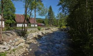 a river with rocks next to a house at Domki OW Rycerka in Rajcza