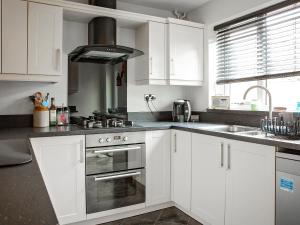 a kitchen with white cabinets and a stove top oven at Pine Hill Lodge in Guisborough