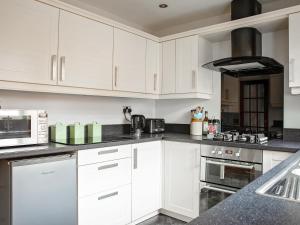 a white kitchen with white cabinets and appliances at Pine Hill Lodge in Guisborough