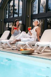 three women sitting by a swimming pool drinking wine at Domki Premium Nautica blisko plaży in Rewal