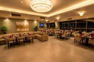 a restaurant with tables and chairs and a chandelier at Al Manzil Hotel Bahrain in Juffair