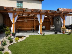 a patio with a bench under a wooden pergola at ViVi Apartments in Liptovský Mikuláš