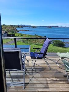 two chairs and a table on a deck overlooking the water at Fjordhytte-24 in Bøvågen