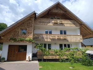 a house with a wooden roof and a balcony at Apartments and rooms Cerkovnik in Bohinj