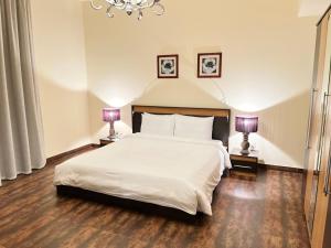 a bedroom with a large white bed with two lamps at Al Manzil Hotel Bahrain in Juffair +42 photos