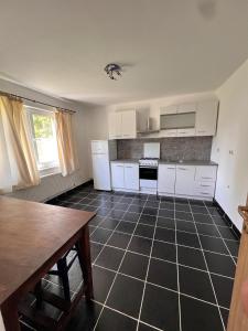 a kitchen with white cabinets and a black tile floor at Vlădești house in Vlădeşti +4 photos