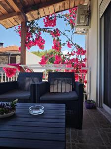 a patio with two chairs and a table with pink flowers at Elina House and Garden in Nikiti