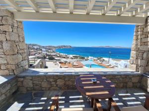 a wooden chair on a balcony with a view of the ocean at Panthea Residence in Agios Ioannis Mykonos
