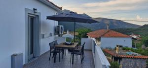 a table and chairs on a balcony with an umbrella at Vrisi House in Kiparission
