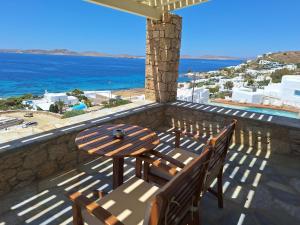 a table and chairs on a balcony overlooking the ocean at Panthea Residence in Agios Ioannis Mykonos