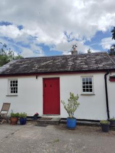 a white house with a red door and plants at New Ross Farm Cottage in New Ross