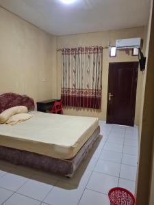 a bedroom with a bed and a chair and a window at Penginapan 369 in Sentani