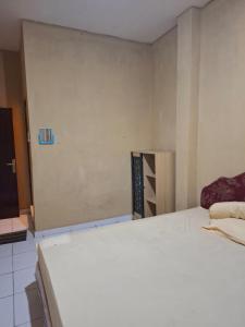 a bedroom with a white bed and a wall at Penginapan 369 in Sentani