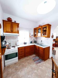 a kitchen with wooden cabinets and a white stove top oven at Ormos Isternia House in Istérnia +16 photos