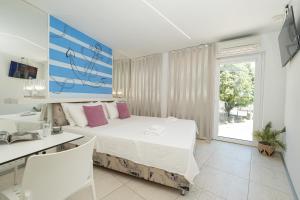 a white bedroom with a large bed and a desk at Avis Hotel in Novalja