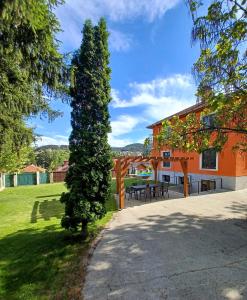 a tree in front of a building with a patio at Hedgehog Villa - Вила Таралеж in Velingrad