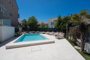a swimming pool in a yard with chairs and a fence at Avis Hotel in Novalja