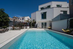 a swimming pool in front of a house at Avis Hotel in Novalja