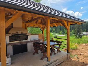 a wooden pavilion with a picnic table and a grill at Apartmani Suncani breg Tara in Mitrovac
