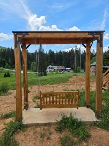 a swinging bench in a park with a field at Apartmani Suncani breg Tara in Mitrovac
