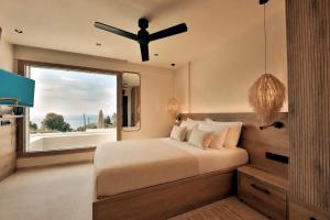 a bedroom with a bed and a ceiling fan at La Brise Luxury Suites in Nea Peramos