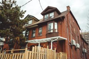 an old red brick house with a wooden fence at Pembroke suites in Toronto
