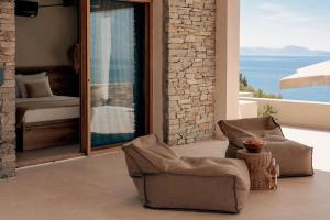 a living room with a chair and a balcony at La Brise Luxury Suites in Nea Peramos