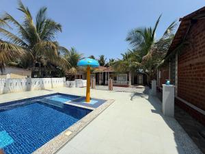 a pool with an umbrella next to a house at Baga Beach Palm Cottage in Calangute
