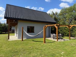a small house with a hammock in the yard at Domek Matyjówka in Ustrzyki Dolne