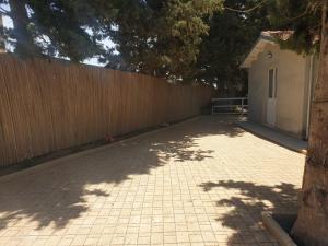 a fence next to a brickicked sidewalk next to a tree at Casa via maucini in Pachino