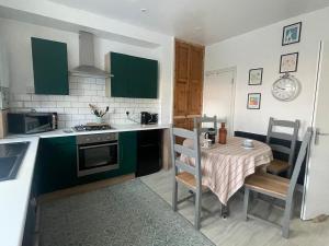 a kitchen with a table and a kitchen with green cabinets at Cozy House in Crookes in Walkly