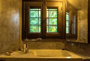 a bathroom with a large tub with a window at Αrnica Montana in Tsagarada