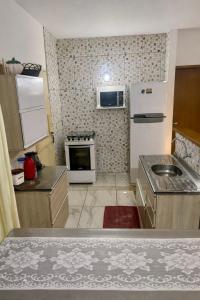 a small kitchen with a stove and a microwave at Casa em Ilha Comprida in Ilha Comprida