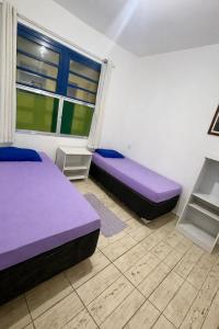 two beds in a room with purple beds at Casa em Ilha Comprida in Ilha Comprida +3 photos