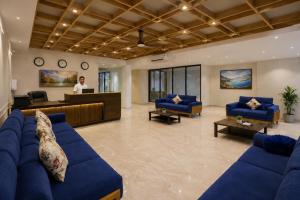a lobby with blue couches and a man standing in the lobby at Hotel West Residency Delhi Airport in New Delhi