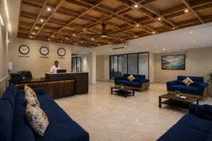 a man standing at a counter in a lobby with blue couches at Hotel West Residency Delhi Airport in New Delhi