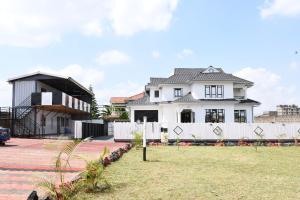 a white house with a fence in a yard at Progressive Success Residency in Juja