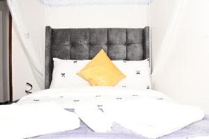 a bed with a black headboard and white pillows at Progressive Success Residency in Juja