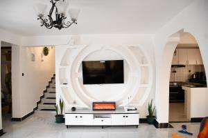 a living room with a tv on a wall at Progressive Success Residency in Juja