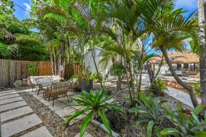 a patio with chairs and palm trees and a fence at Inn On The Drive in Fort Lauderdale