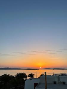 Una puesta de sol sobre el agua con casas y árboles. en Apsenti couples only, en Agios Ioannis Mykonos