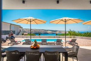 a patio with a table with chairs and umbrellas at Villa Amarea in Lopar