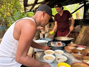 two men preparing food on a table with bowls of food at Natural Suites ENSUEÑOS Natural Reserve in Little Corn Island